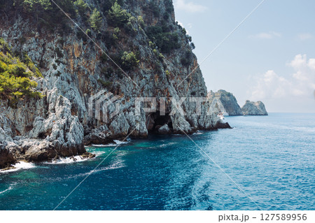 Beautiful seascape with a ship. Sea voyage. rocky shore with turquoise transparent water. Picturesque natural landscape with rough texture, Ecotourism. Fascinating seascape. 127589956