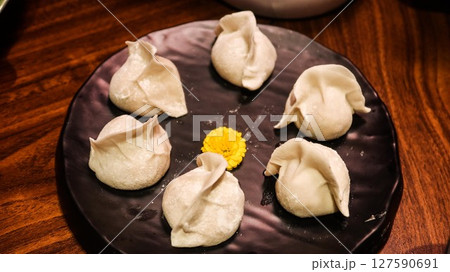 close up of six uncooked raw pork dumplings (Jiaozi or Gyoza) on a plate with a yellow flower in the middle for decoration close up of six uncooked raw pork dumplings (Jiaozi or Gyoza) on a plate with a yellow flower in the middle for decoration 127590691