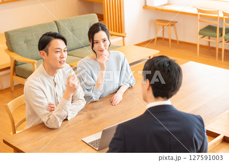 リビングで商談するビジネスマンと若い夫婦 127591003