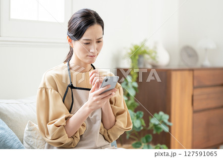 スマホを見ながら悩む女性 127591065