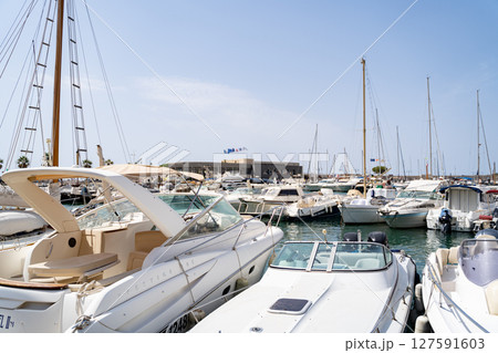 The marina is filled with luxurious yachts against backdrop of a clear blue sky 127591603