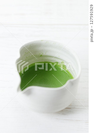 Cup of fresh matcha tea, green tea on white wooden table. Cup of fresh matcha tea, green tea on white wooden table. 127591929
