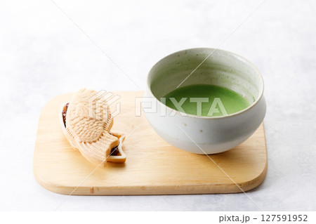 Cup of fresh matcha tea, green tea and Taiyaki, Japanese fish-shaped cake, filled with Anko or red bean on wooden plate. 127591952