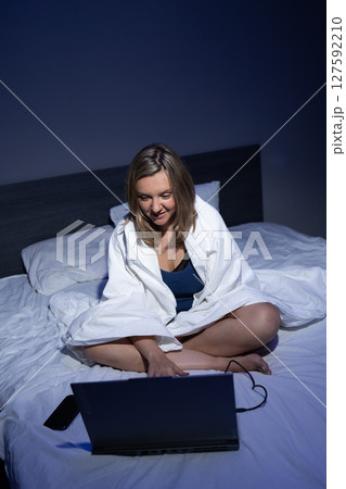 Young Woman Using Laptop While Sitting on Bed in Dimly-Lit Room During Nighttime Young Woman Using Laptop While Sitting on Bed in Dimly-Lit Room During Nighttime 127592210