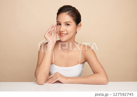 A beautiful young Asian woman with clean, fresh skin against a beige background. Skincare, facial treatment, cosmetology, beauty, and spa. An elegant portrait of an Asian woman. A beautiful young Asian woman with clean, fresh skin against a beige background. Skincare, facial treatment, cosmetology, beauty, and spa. An elegant portrait of an Asian woman. 127592745