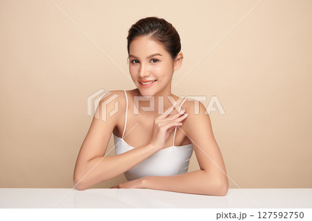 A beautiful young Asian woman with clean, fresh skin against a beige background. Skincare, facial treatment, cosmetology, beauty, and spa. An elegant portrait of an Asian woman. A beautiful young Asian woman with clean, fresh skin against a beige background. Skincare, facial treatment, cosmetology, beauty, and spa. An elegant portrait of an Asian woman. 127592750