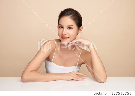 A beautiful young Asian woman with clean, fresh skin against a beige background. Skincare, facial treatment, cosmetology, beauty, and spa. An elegant portrait of an Asian woman. A beautiful young Asian woman with clean, fresh skin against a beige background. Skincare, facial treatment, cosmetology, beauty, and spa. An elegant portrait of an Asian woman. 127592759