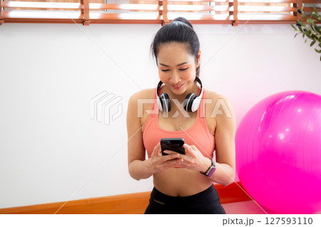 Young asian woman watching smartphone for practice yoga and workout in living room at home. Young asian woman watching smartphone for practice yoga and workout in living room at home. 127593110