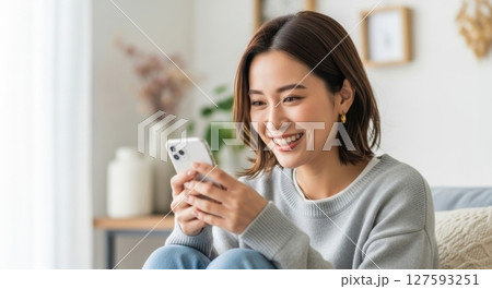 くつろぎながらスマホ操作する女性素材 127593251