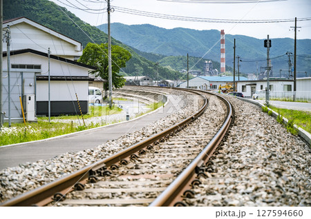 カーブする線路と工場のある日本の郊外風景 127594660