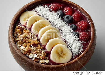 Summer dish. Colorful acai bowl with banana slices, coconut flakes and granola on a white background. Healthy and Wellness Breakfast for luxury resorts. Summer dish. Colorful acai bowl with banana slices, coconut flakes and granola on a white background. Healthy and Wellness Breakfast for luxury resorts. 127594683