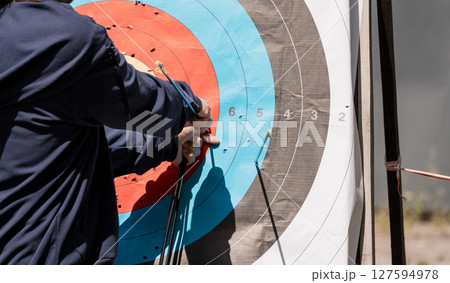 Archery Practice Shot, Outdoor Target Range, Concentrated Archer, Blue and Red Bullseye, Sports Training, Precision Skill, Recreational Activity. 127594978