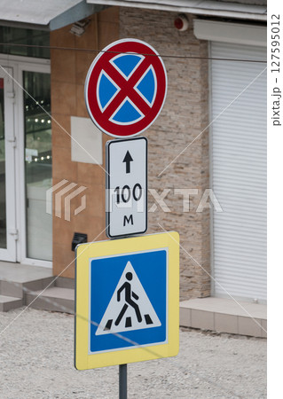 Street Signage Cluster Featuring No Parking Restriction, Pedestrian Crossing Warning, and Distance Indicator in Urban Environment, Brick Texture 127595012