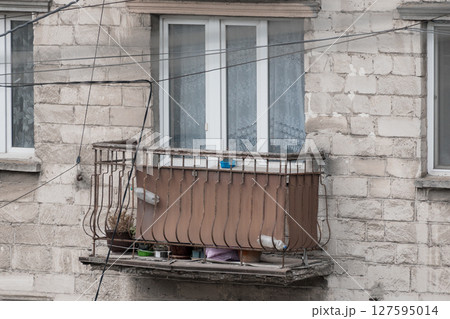 Urban Balcony Still Life with Pigeons: Rusty Metal Railing, Net Curtains, and Concrete Facade in Pale Grey Tones Urban Balcony Still Life with Pigeons: Rusty Metal Railing, Net Curtains, and Concrete Facade in Pale Grey Tones 127595014