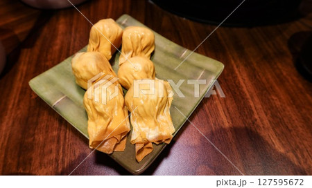 Show title suggestion close up of six pieces of uncooked raw shrimp and pork stuffed dumplings on a plate on a wooden table with copy space Show title suggestion close up of six pieces of uncooked raw shrimp and pork stuffed dumplings on a plate on a wooden table with copy space 127595672