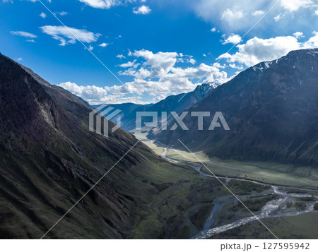 Scenic view of Chulyshman River Valley in Altai. lush green vegetation and towering mountains under cloudy sky. Travel and landscape photography. Scenic view of Chulyshman River Valley in Altai. lush green vegetation and towering mountains under cloudy sky. Travel and landscape photography. 127595942