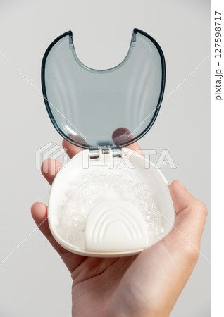 Braces. Invisible aligners. White background, close-up. Transparent aligners for teeth jaws. Transparent dental aligners on a white storage case. Prevention treatment of gums 127598717