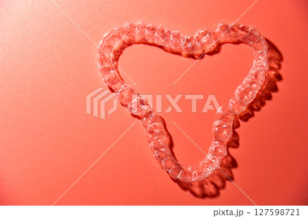 Close up of invisible aligners on pink background with copy space. Plastic braces dental retainers for teeth straightening 127598721