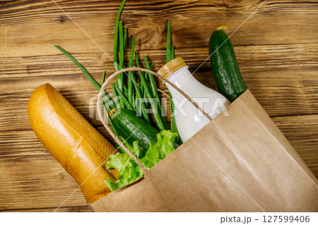 Paper bag with different food on wooden table. Top view. Grocery shopping concept 127599406