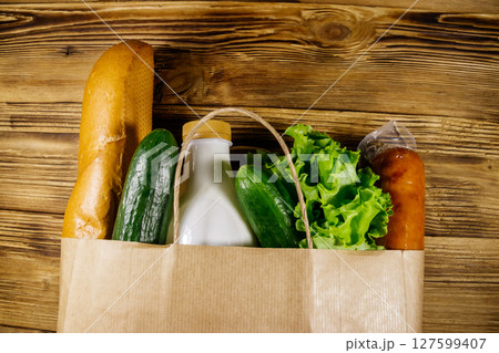 Paper bag with different food on wooden table. Top view. Grocery shopping concept 127599407