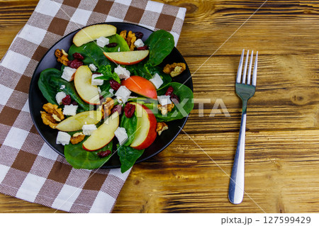 Autumn spinach salad with apple, feta cheese, walnut and dried cranberry on wooden table. Top view. Healthy vegetarian food 127599429