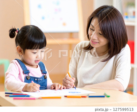 お絵描きをする子供と女性保育士 127599513