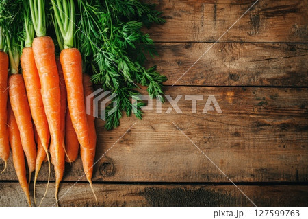 A bunch of carrots and green leaves are on a wooden table. Concept of freshness and natural beauty A bunch of carrots and green leaves are on a wooden table. Concept of freshness and natural beauty 127599763