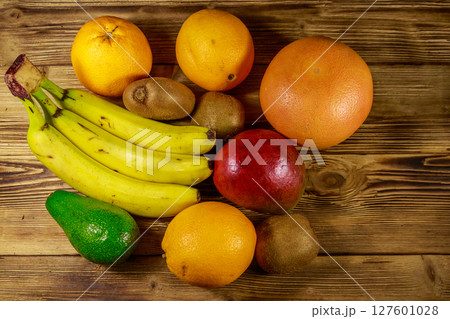 Assortment of tropical fruits on wooden table. Still life with bananas, mango, oranges, avocado, grapefruit and kiwi fruits 127601028