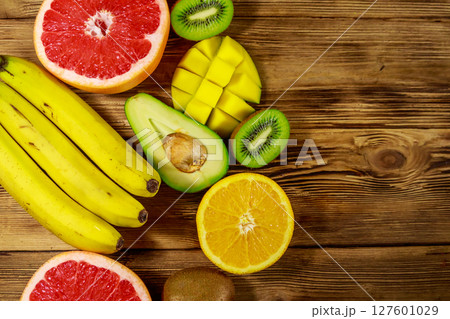 Assortment of tropical fruits on wooden table. Still life with bananas, mango, oranges, avocado, grapefruit and kiwi fruits 127601029