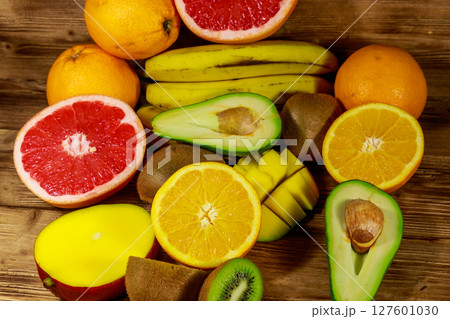 Assortment of tropical fruits on wooden table. Still life with bananas, mango, oranges, avocado, grapefruit and kiwi fruits Assortment of tropical fruits on wooden table. Still life with bananas, mango, oranges, avocado, grapefruit and kiwi fruits 127601030