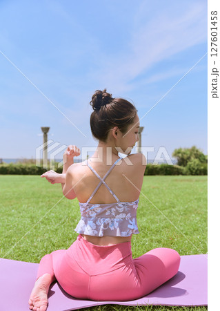 天然芝と青空の下、リゾート気分でヨガ＆ピラティスをする女性 127601458