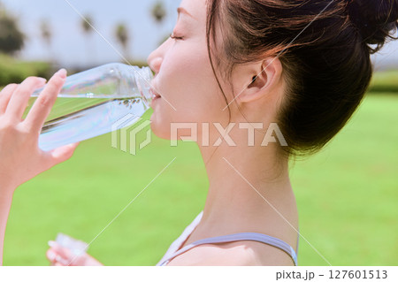 青空の天然芝でヨガ後に水分補給をする健康的 127601513