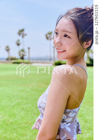 青空の天然芝でヨガ後に水分補給をする健康的な女性 青空の天然芝でヨガ後に水分補給をする健康的な女性 127601519