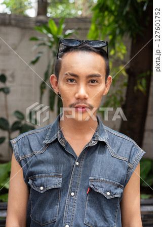 Portrait of nonbinary genderfluid young Asian gay man sitting outdoors Portrait of nonbinary genderfluid young Asian gay man sitting outdoors 127601752