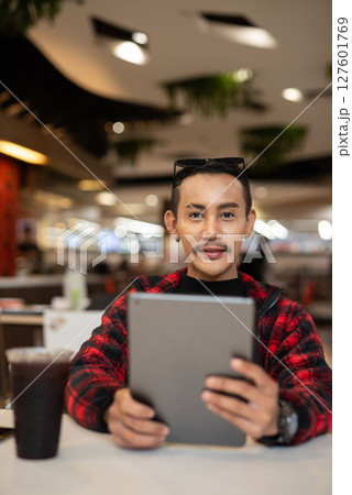 Portrait of nonbinary genderfluid young Asian gay man using digital tablet computer 127601769