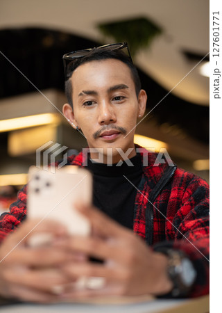 Portrait of nonbinary genderfluid young Asian gay man texting with phone Portrait of nonbinary genderfluid young Asian gay man texting with phone 127601771