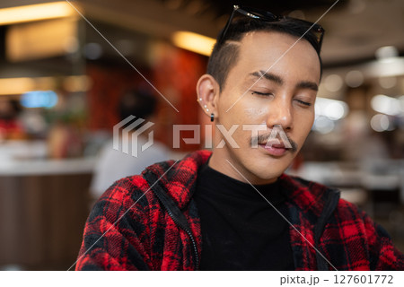 Portrait of nonbinary genderfluid young Asian gay man relaxing with eyes closed Portrait of nonbinary genderfluid young Asian gay man relaxing with eyes closed 127601772