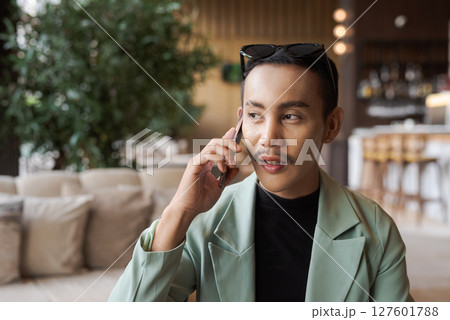 Portrait of nonbinary genderfluid young Asian gay businessman using phone in cafe 127601788