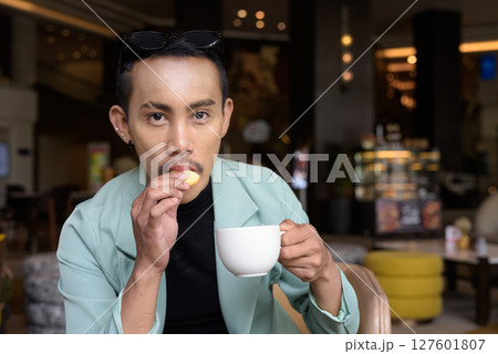 Portrait of nonbinary genderfluid young Asian gay man drinking coffee 127601807