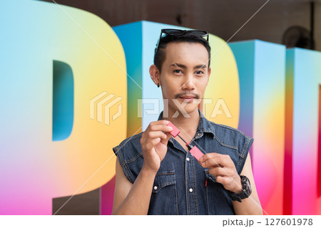 Portrait of confident non binary gay man holding lipstick Portrait of confident non binary gay man holding lipstick 127601978