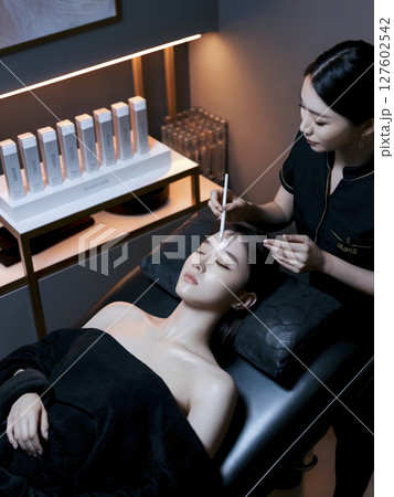 Woman is getting her face done by another woman Woman is getting her face done by another woman 127602542