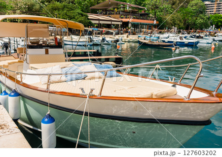 Small boats floating in marina with mountain backdrop. Coastal lifestyle, nautical tourism, and scenic summer destination. 127603202