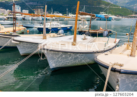 Small motorboats docked in calm marina water. Seaside lifestyle, coastal transportation, and nautical summer atmosphere Small motorboats docked in calm marina water. Seaside lifestyle, coastal transportation, and nautical summer atmosphere 127603204