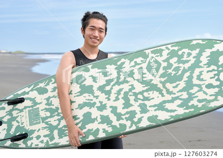 サーフボードを持って笑顔を見せる若い男性 127603274