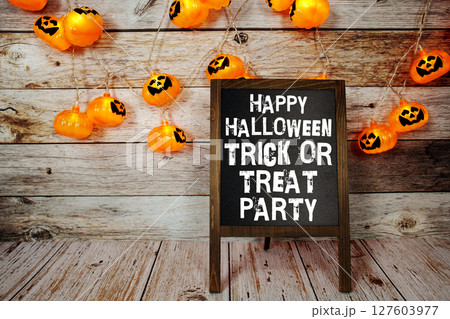 Happy Halloween Trick or Treat text on blackboard easel with LED pumpkin decoration on wooden background 127603977