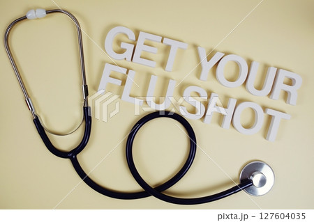 Get Your Flu Shot alphabet letters with stethoscope top view on yellow background 127604035
