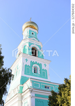 Bell tower of Syzran Kazan Cathedral with golden dome and turquoise facade against blue sky Bell tower of Syzran Kazan Cathedral with golden dome and turquoise facade against blue sky 127604302