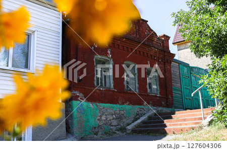Vintage red brick building with green doors, vibrant flowers in foreground creating charming scene 127604306