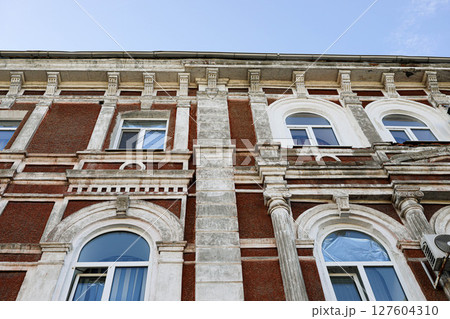 Historic brick building facade with ornate architectural details and blue sky above Historic brick building facade with ornate architectural details and blue sky above 127604310