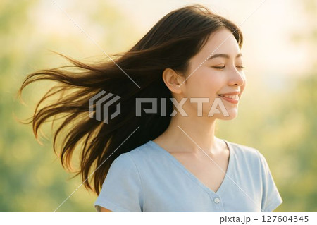 風に髪をなびかせる笑顔の女性のポートレート 127604345